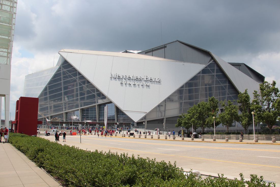 Angular silver and glass exterior of Mercedes-Benz Stadium under a cloudy sky