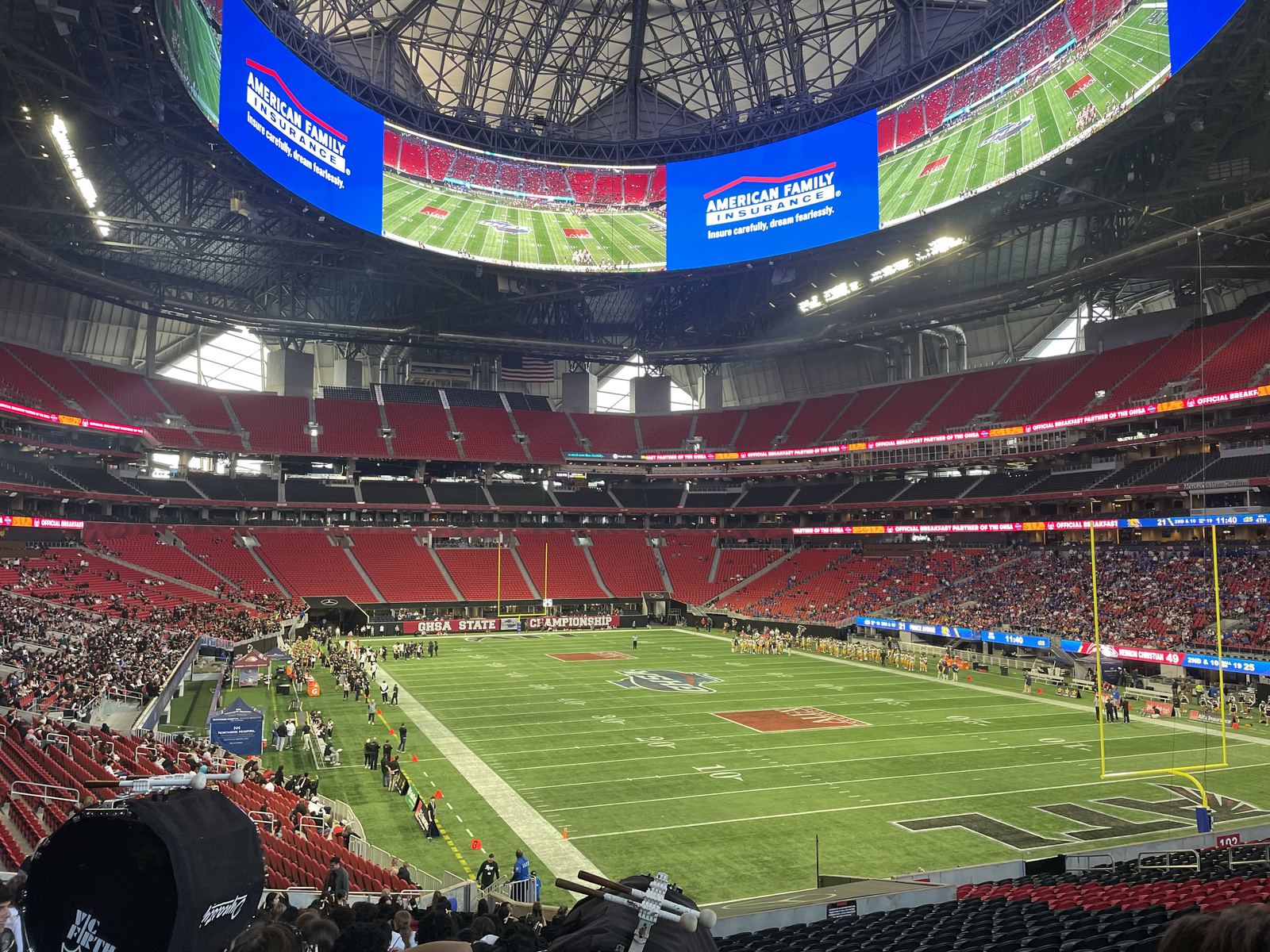 Football field inside Mercedes-Benz Stadium with red seats and the circular halo video board overhead