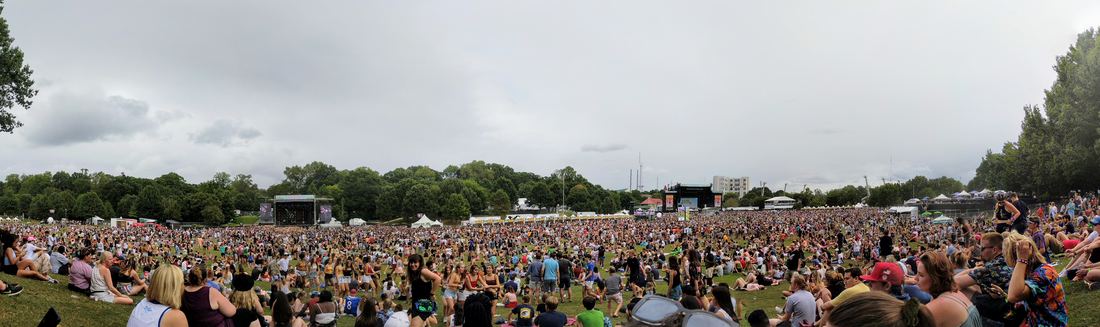 Panoramic view of a festival crowd filling the Piedmont Park Meadow in front of two stages