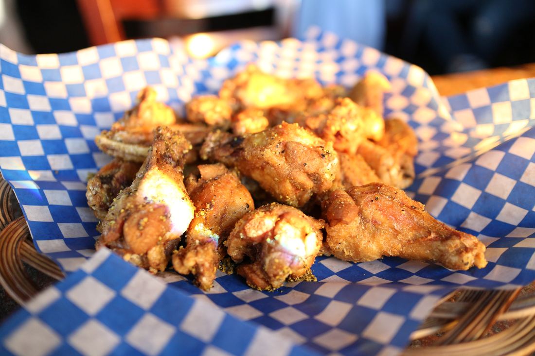 Basket of lemon pepper chicken wings on blue checkered paper