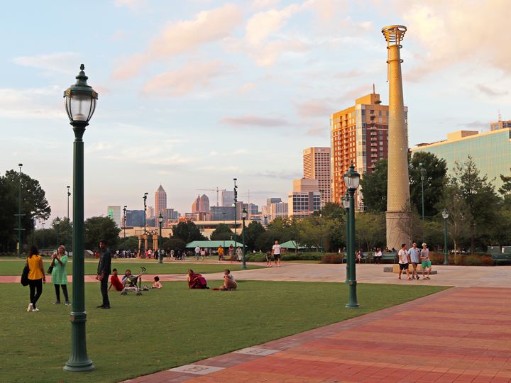 Lawn, lampposts and a tall commemorative column in Centennial Olympic Park at sunset