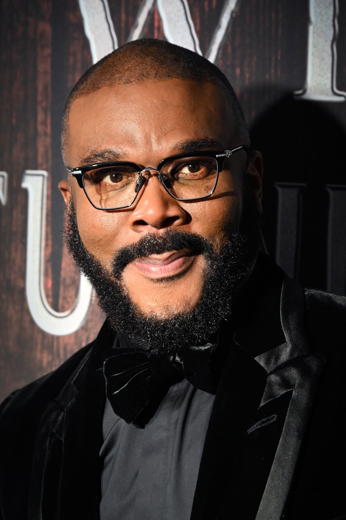 Tyler Perry in glasses and a black velvet jacket with bow tie at a premiere