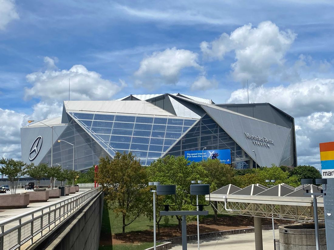 Mercedes-Benz Stadium seen from Centennial Olympic Park Drive under a blue sky